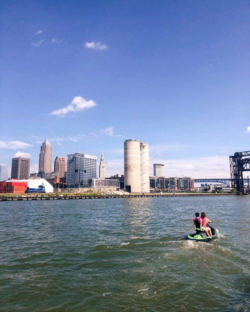 Jet Skiiers on the Cuyahoga River off of Lake Erie with Cleveland skyline and blue skies.