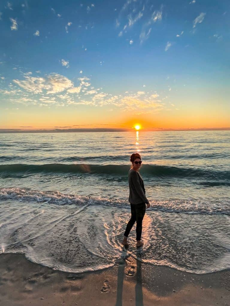 girl walking along the shore of the gulf of mexico at sunset